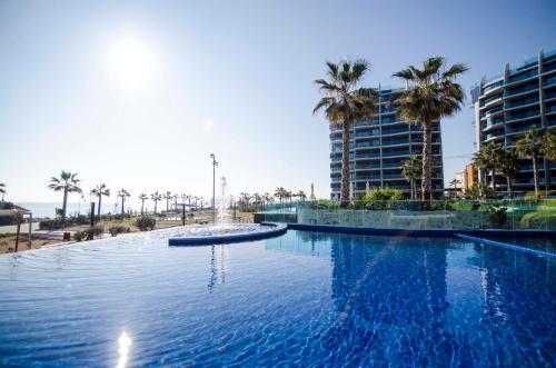 una gran piscina con palmeras y un edificio en Sea Senses by Mar Holidays, en Torrevieja