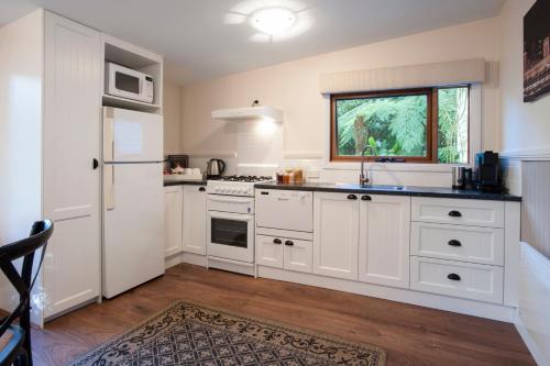 a kitchen with white cabinets and a sink at Clarendon Cottages in Sassafras