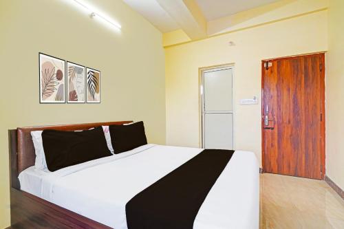a bedroom with a white bed and a wooden door at Super Hotel O Srigandhakavalu formerly Chamundeshwari Lodging in Bengaluru