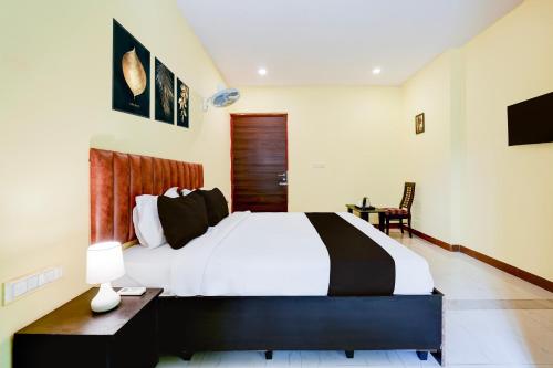 a bedroom with a large bed and a desk with two lamps at Super Hotel O Hennagara Rd Bommasandara in Bengaluru