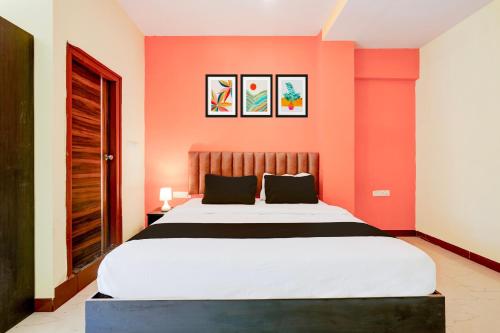 a bedroom with a large bed with orange walls at Super Hotel O Hennagara Rd Bommasandara in Bengaluru