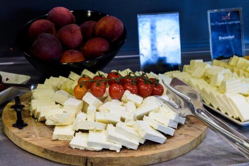 a plate of cheese and tomatoes and a bowl of fruit at HOTEL CARPAT INN in Azuga