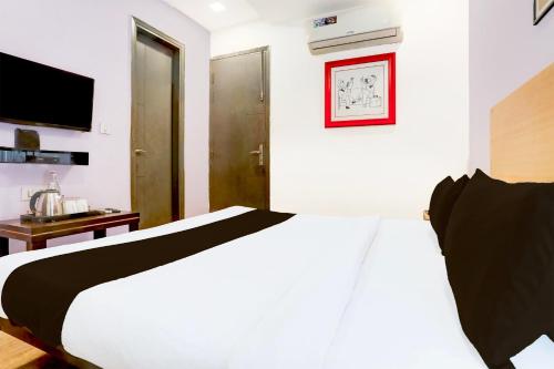 a bedroom with a white bed and a television at Super Townhouse Rohini Sector 24 in New Delhi
