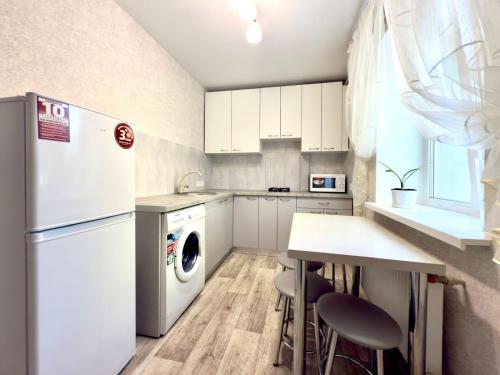 Una cocina con nevera y una mesa con taburetes. en new apartment near the center квартира в новому будинку поруч з центром, en Sumy
