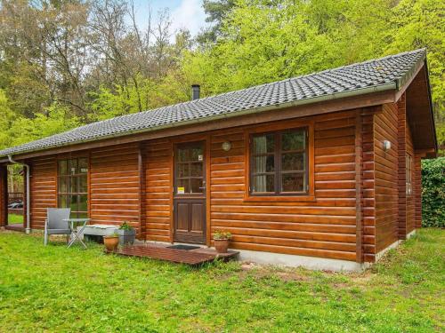 a wooden cabin with a porch in the grass at 4 star holiday home in Ebeltoft in Ebeltoft