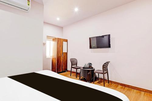 a room with a bed and a table and chairs at Super Hotel O Ramarvapadu Near ESI Hospital in Vijayawada