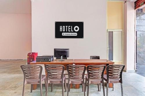 a table with chairs and a sign on the wall at Super Hotel O Ramarvapadu Near ESI Hospital in Vijayawada