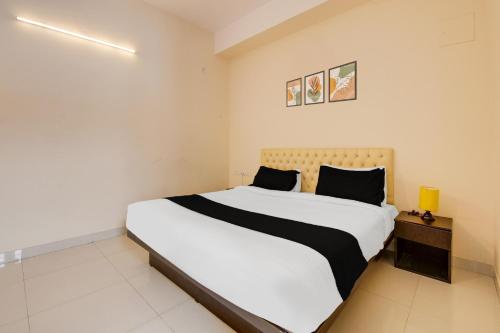 a bedroom with a large white bed with black pillows at Super Townhouse HBR Layout in Bengaluru