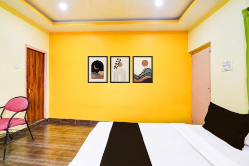 a bedroom with three pictures on a yellow wall at Super Hotel O Daspara Kolkata Formerly Laxmi Guest House in Kolkata