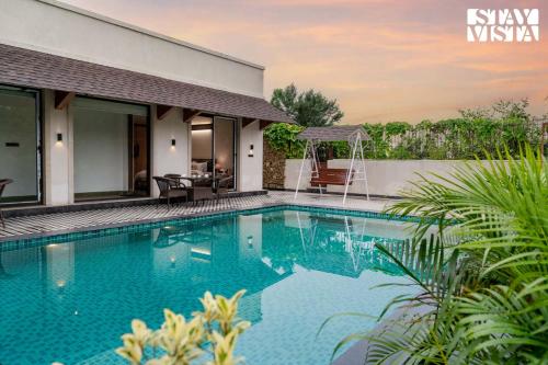 una piscina frente a una casa en StayVista at Rustic Roots with Bonfire, Lawn, en Jaipur