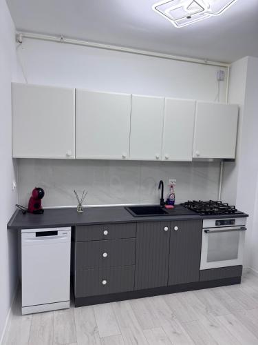 a kitchen with white cabinets and a black counter top at Apartament in Ploiești 6 in Ploieşti