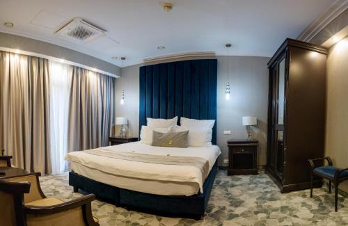 a bedroom with a large bed with blue curtains at HOTEL CARPAT INN in Azuga