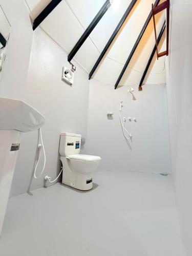 a white bathroom with a toilet and a sink at Tribal Village in Trincomalee
