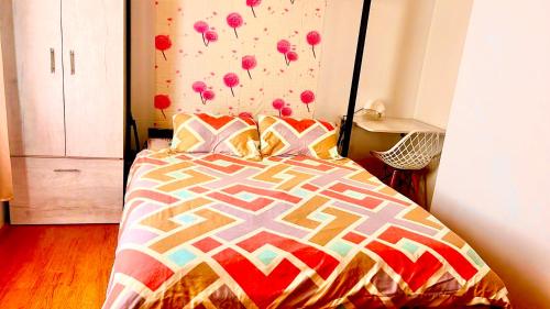 a bed with a colorful comforter in a bedroom at Messatiera Condo - UrbanSol Stay in Davao City