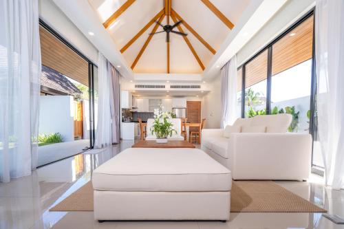 a living room with white furniture and large windows at Anchan Villas Phuket - Private 2 Bedroom Pool Villas by Escape Villas in Bang Tao Beach