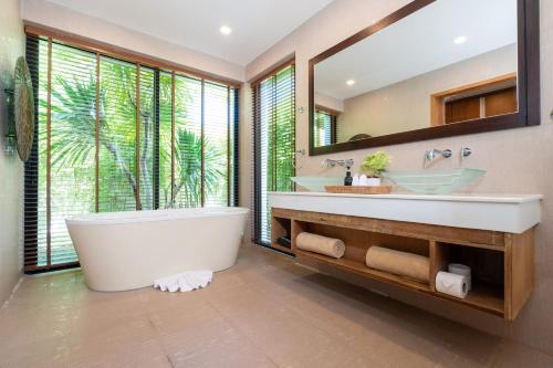 une salle de bain avec une grande baignoire et un grand miroir dans l'établissement Anchan Villas Phuket - Private 2 Bedroom Pool Villas by Escape Villas, à Ban Phru Champa