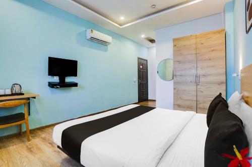 a bedroom with a large bed and a tv on the wall at Super Townhouse Rohini Sector 23 in New Delhi