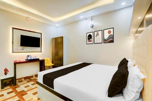 a bedroom with a bed and a desk and a tv at Super Collection O Jagdeo Path Patna in Patna