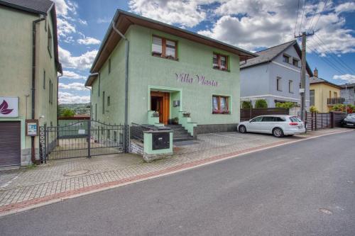 a green building with a car parked in front of it at Villa Vlasta in Karlovy Vary