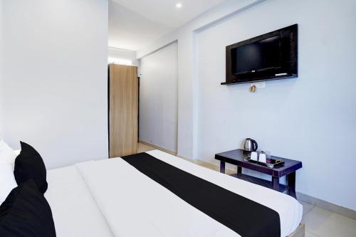 a bedroom with a bed with a tv on the wall at Super Hotel O BLW Kakarmatta Near Banaras Junction in Varanasi