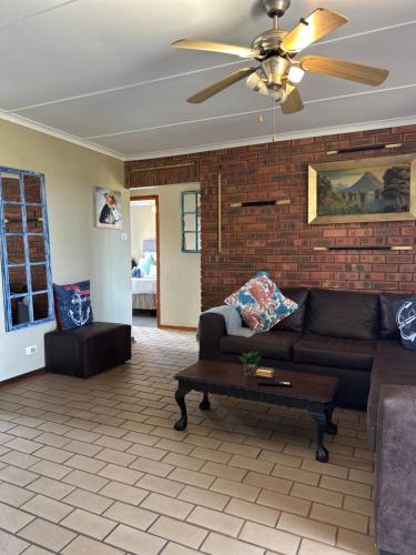 a living room with a couch and a ceiling fan at BlueHive guesthouse Leisure in Port Edward