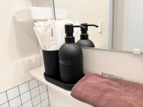 zwei schwarze Flaschen auf einem Regal im Badezimmer in der Unterkunft Hotel chen's house - Vacation STAY 42508v in Tokio