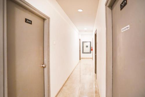 a hallway with white walls and a long hallway with a door at Super Hotel O Hingna Road Wanadongri in Nagpur