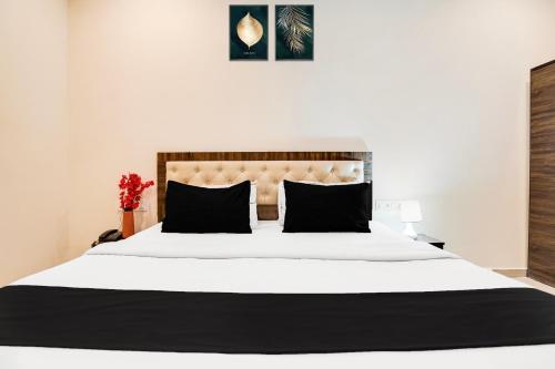 a bedroom with a large white bed with black pillows at Super Hotel O Hingna Road Wanadongri in Nagpur