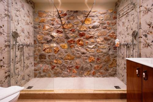 a bathroom with a shower with a stone wall at NafplioBiofarms Country Apartments in Nafplio