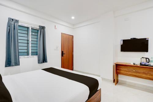 a white bedroom with a bed and a television at Super Collection O Brookefield Central Formerly Bangalore Inn in Bengaluru