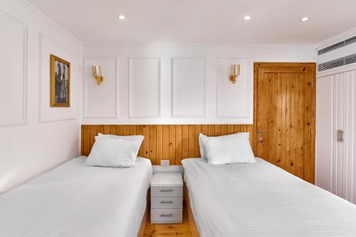 two beds in a room with white walls and wood at Fatima Dahabiya in Luxor