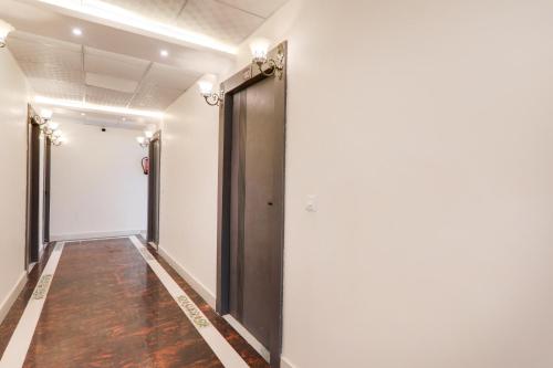 a corridor with white walls and a black door at Super Collection O Quila Road Formerly JR Inn in Lucknow