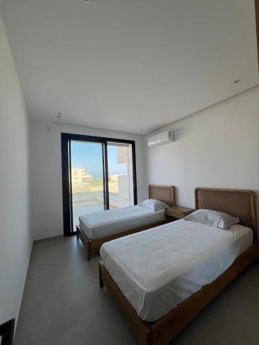 due letti in una stanza con una grande finestra di Villa Ryma a Ḩammām al Ghazzāz