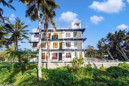 a building on a hill with palm trees at Super Hotel O Kazhakuttam Vadakkumbhagam in Trivandrum