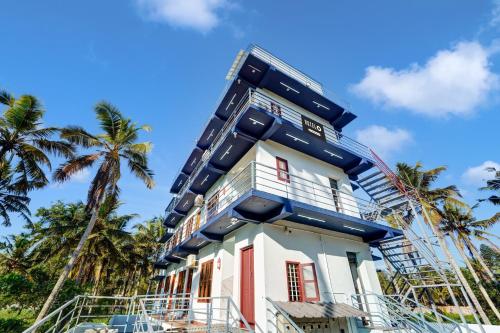 a building with palm trees in front of it at Super Hotel O Kazhakuttam Vadakkumbhagam in Trivandrum