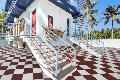 a staircase leading to a house with a checkered floor at Super Hotel O Kazhakuttam Vadakkumbhagam in Trivandrum