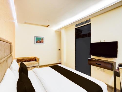a hotel room with a bed and a flat screen tv at Super Townhouse Pitampura West Enclave in New Delhi