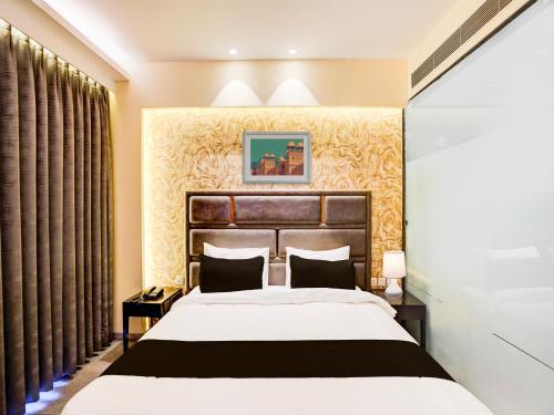 a bedroom with a large bed and curtains at Super Townhouse Pitampura West Enclave in New Delhi