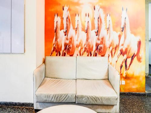 a white couch in front of a painting of horses at Super Townhouse Pitampura West Enclave in New Delhi