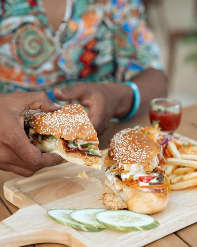 a person holding a sandwich and french fries on a cutting board at Kinan Boutique in Fulidhoo