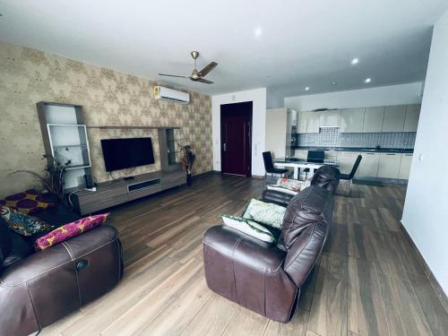 a living room with a leather couch and a television at Henrietta's Residence, Cantonments in Accra