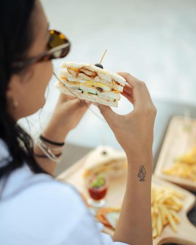 a woman eating a sandwich with a tattoo on her arm at Kinan Boutique in Fulidhoo