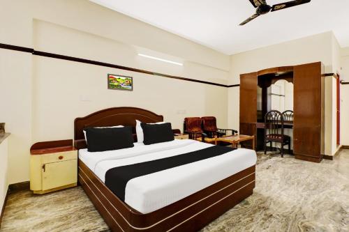 a bedroom with a bed and a desk in a room at Super Hotel O East Nada in Guruvāyūr