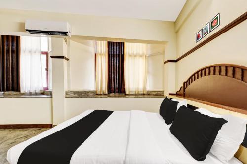 a bedroom with a large white bed and two windows at Super Hotel O East Nada in Guruvāyūr