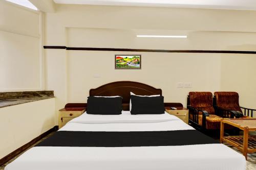 a bedroom with a large bed and two chairs at Super Hotel O East Nada in Guruvāyūr