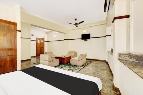 a hotel room with a bed and chairs and a tv at Super Hotel O East Nada in Guruvāyūr