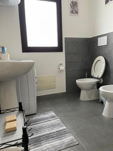 a bathroom with a sink and a toilet and a window at L&C hideaway in Sestu