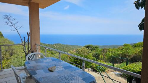 a table and chairs on a balcony with a view at Sari- Vue mer- climatisation in Sari Solenzara