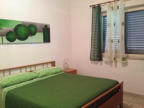 a bedroom with a green bed and a window at Ricciardulli Rooms in Policoro