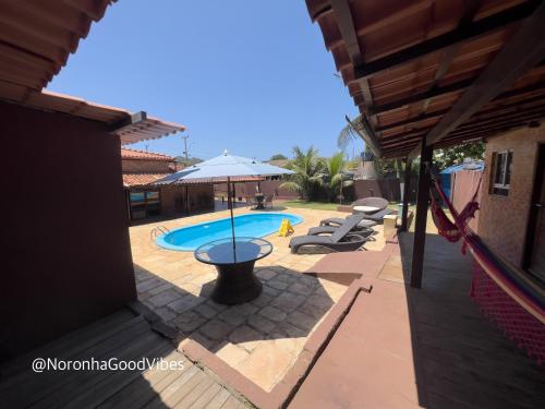 a patio with a pool and an umbrella at Noronha Good Vibes Hostel in Fernando de Noronha